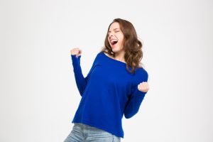 Excited delighted young woman shouting and celebrating success over white background